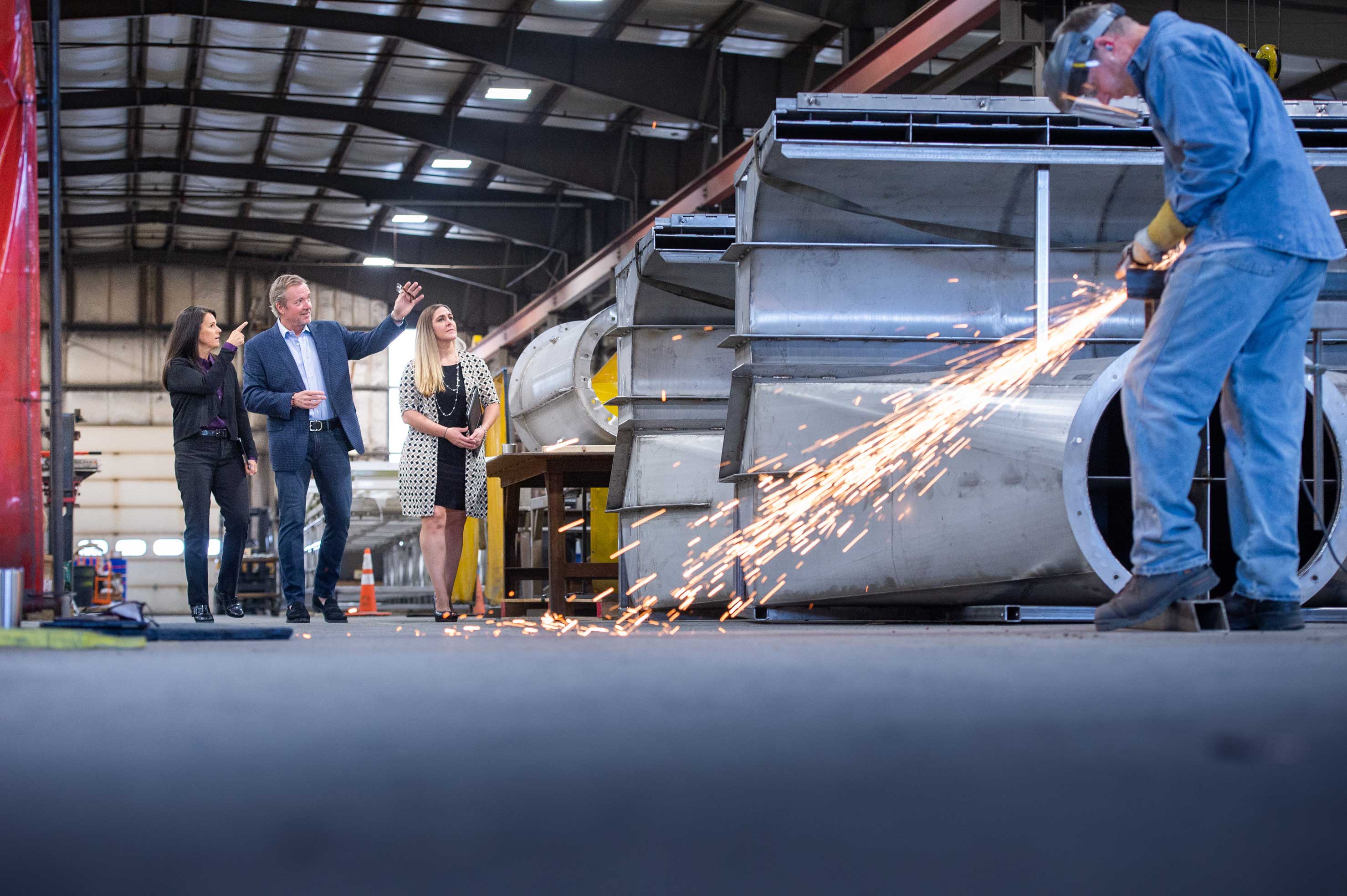 BST advisors tour inside a client warehouse where an employee is welding equipment in the foreground